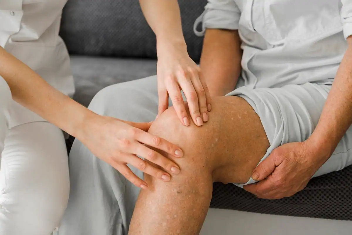 Medic care examinează genunchiul unui pacient în timpul unui consult pentru a doua opinie