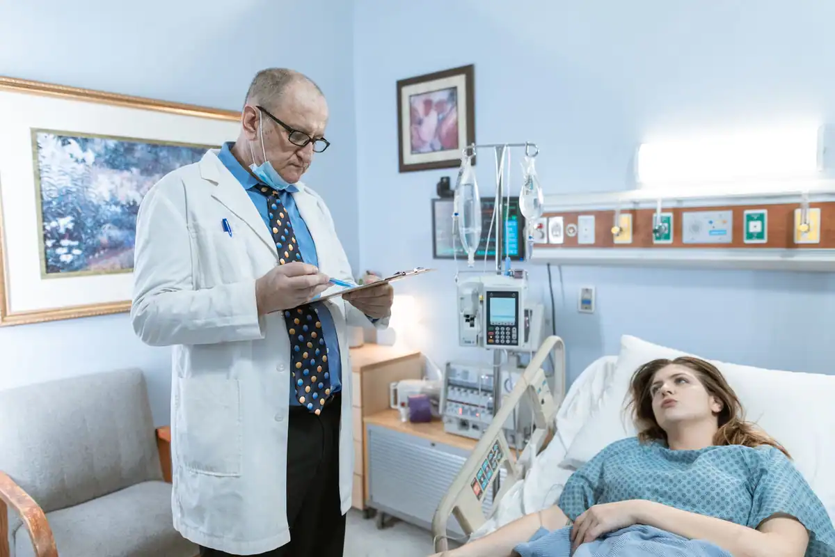 Medic în halat alb consultă fișa unui pacient într-un salon de spital