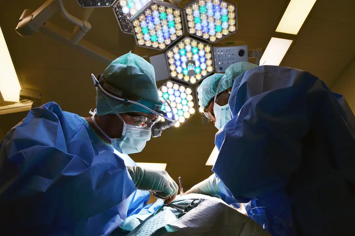 Echipă chirurgicală în sala de operație, sub lămpile mari ale blocului operator