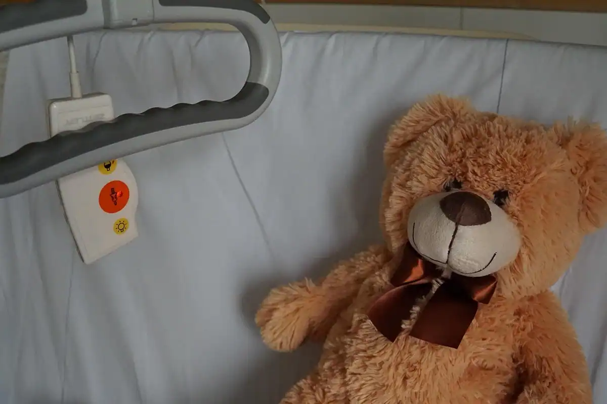Ursuleț de pluș așezat pe patul de spital al unui copil