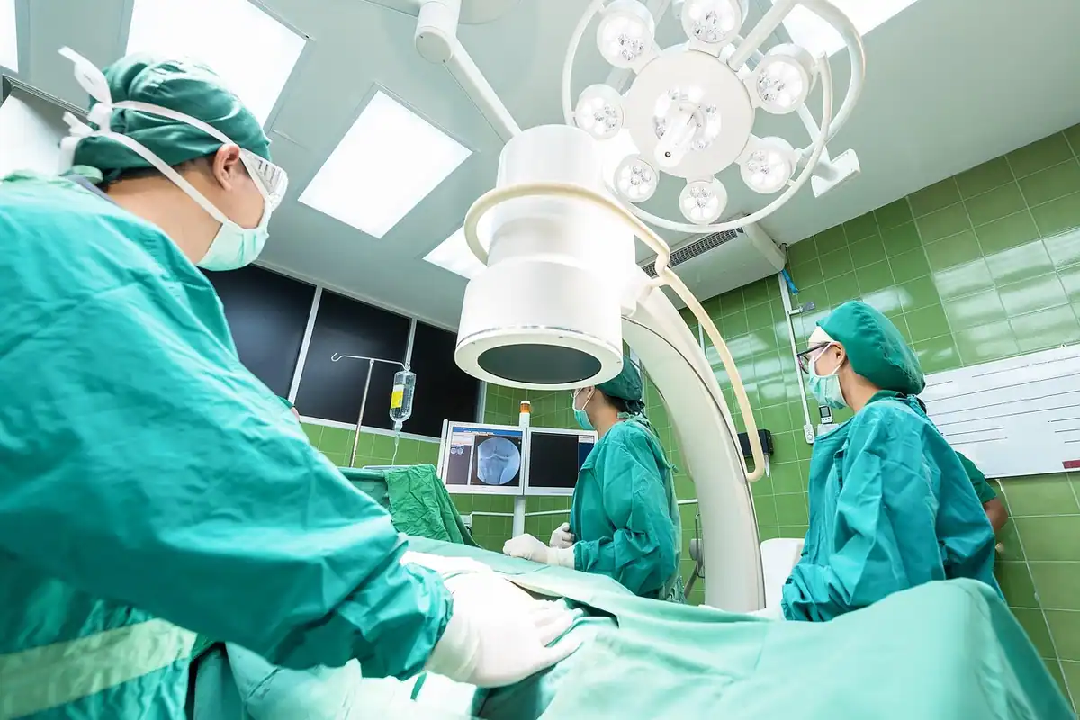 Echipă chirurgicală în halate verzi, lucrând într-o sală de operație