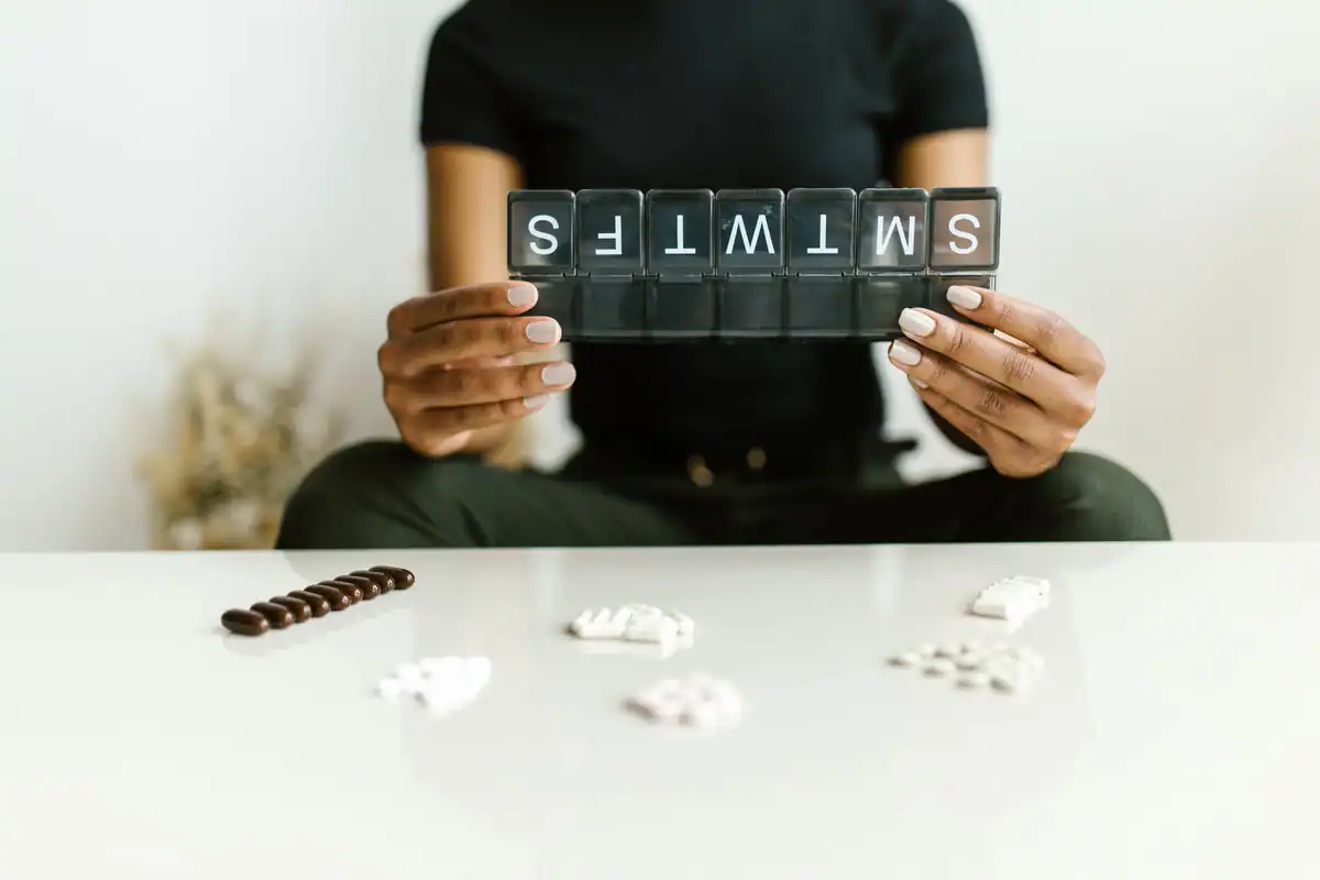 Organizator cu zilele săptămânii ținut în mâini, lângă câteva pastile