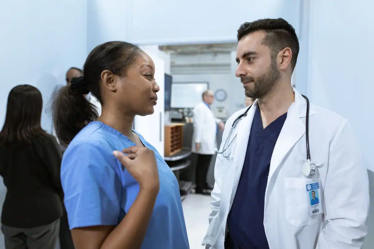Asistentă și medic discută pe hol, într-o secție de spital