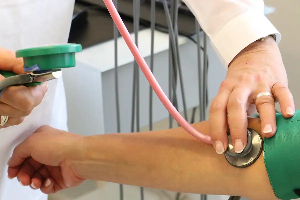 Medic ia tensiunea brațului unui pacient cu tensiometru și stetoscop