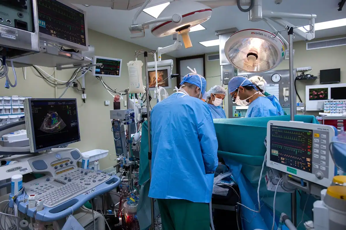 Echipă medicală în sala de operație, lângă monitoare și aparatură de anestezie